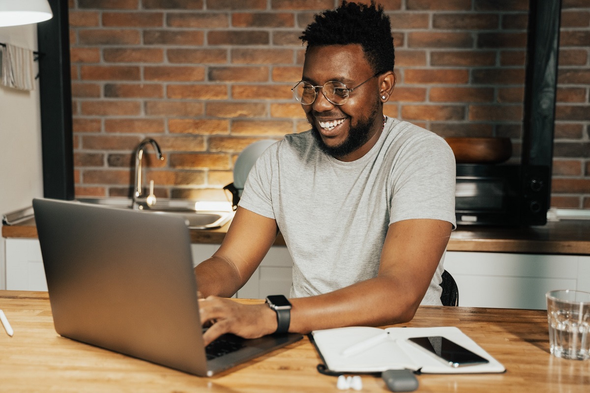  A freelancer smiles while using a laptop to search for industry events to attend to expand their professional network.
