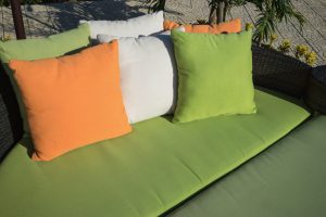 Tricolor outdoor pillows on sofa under bright sunlight