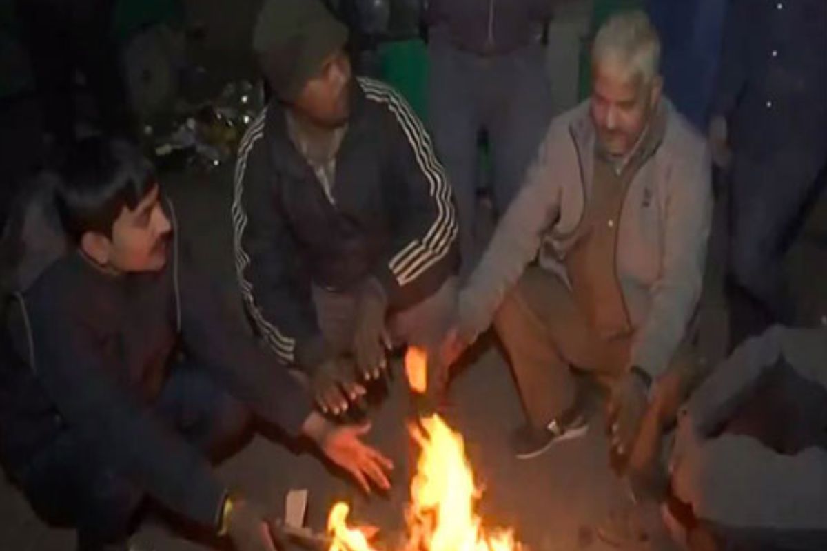 Cold weather grips Delhi, people huddle around bonfires to keep themselves warm