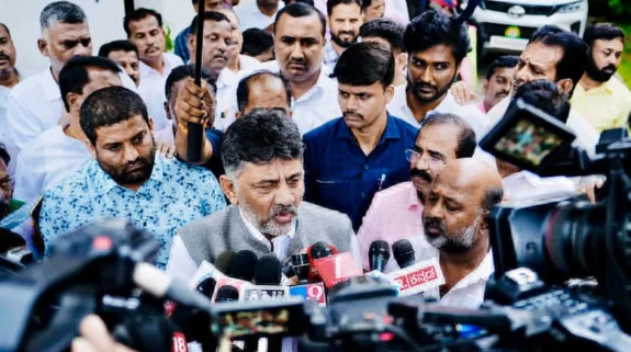 Karnataka Deputy Chief Minister DK Shivakumar speaking to reporters while surrounded by supporters and media personnel in Bengaluru.