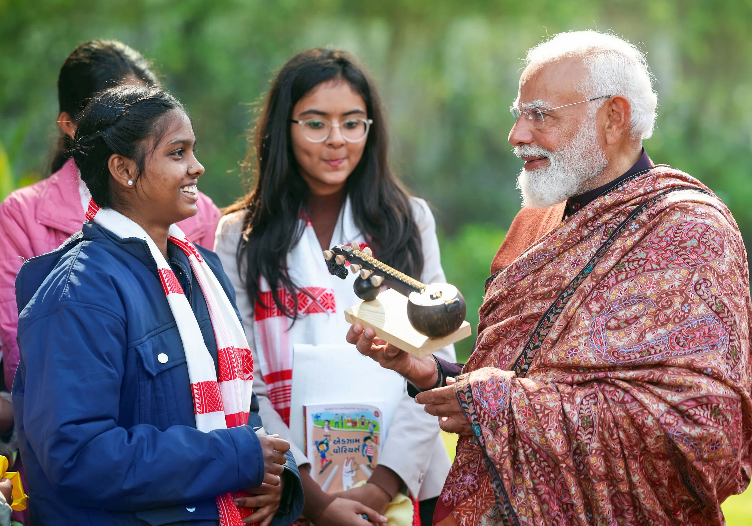 PM Modi receives a handcrafted gift from a student as others look on with smiles during the interactive session. img