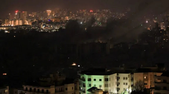 Smoke rises over a city skyline after reported airstrikes amid US-Israel-Iran conflict