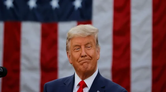 Donald Trump standing in front of the US flag during a public appearance