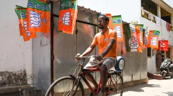 Man riding a bicycle past BJP, TMC and CPI(M) flags in Kolkata during West Bengal Assembly elections