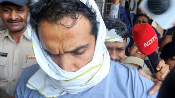 Accused Samarth Singh being escorted by police and surrounded by media personnel outside a court in Bhopal