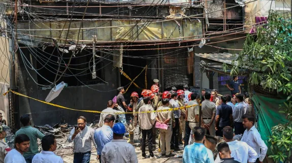 Firefighters and police personnel inspect the charred Malviya Nagar hotel building after the deadly blaze that killed 21 people in New Delhi.
